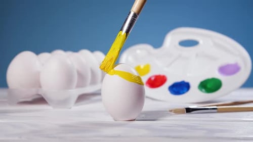 Painting Easter Eggs with a Yellow Brush Preparation for Spring Holiday Religious Celebration Art