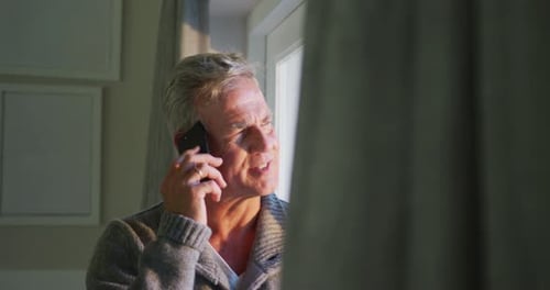 Man Chatting on Phone Indoors by Window