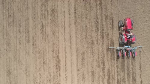Red Tractor Cultivating Vast Rural Field from Above