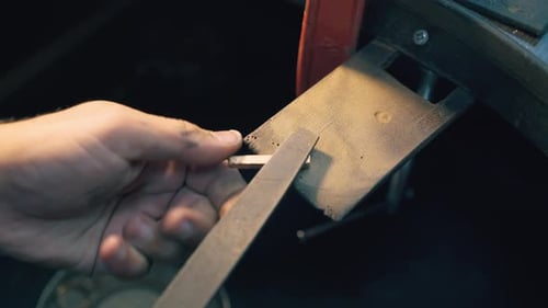 Jeweler Polishes Gold Bar with Rasp at Workplace Closeup