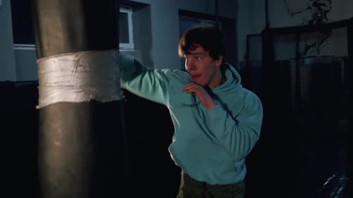 Alone Boxer Hits Punching Bag in Dark Gym in Slow Motion