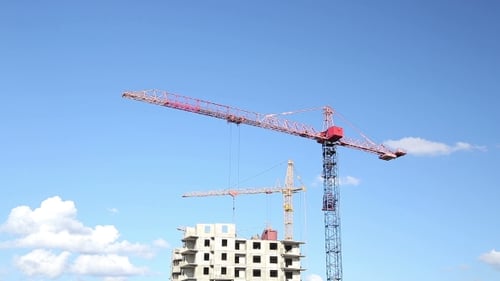 Cranes Working On Construction Site Under Cloudy Sky