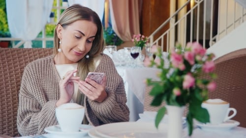Woman Using Phone at Cafe Table