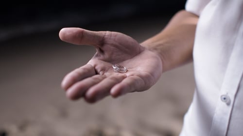 Hand Holds Engagement Ring on Beach at Night