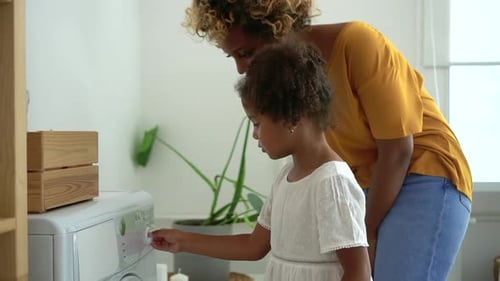American Woman and Laundry Wash Machine Cloth Teach and Tell Young Daughter How to Start Washing