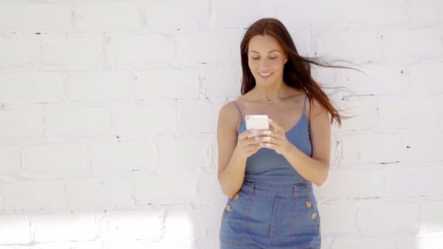 Beautiful Brunette Woman Using Phone Against Brick Wall