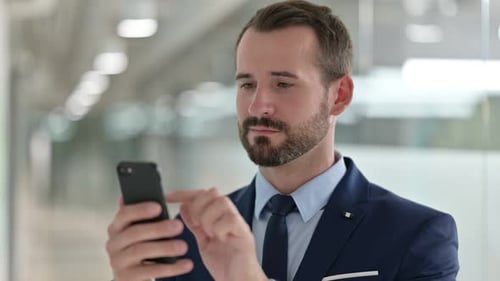 Young Adult Businessman Using Smartphone in Office