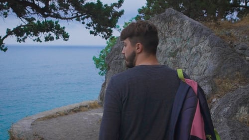 Man Walking on Trail by Sea Coast