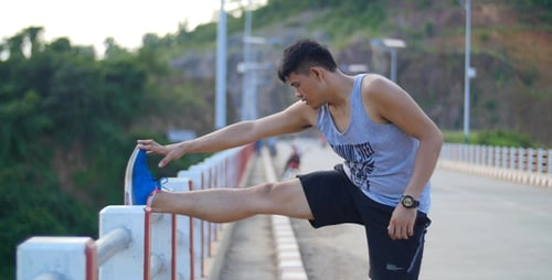 Man Stretches Leg on Bridge Before Workout