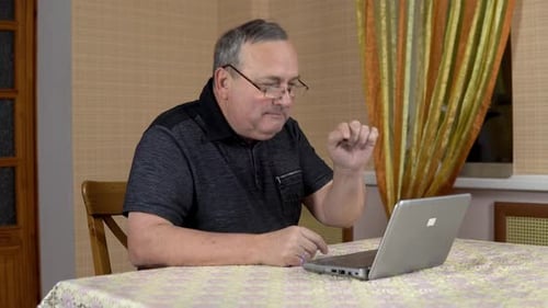 Senior Man Using Laptop at Table Indoors