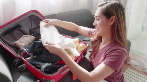 Woman Packing Suitcase with Clothing for Travel