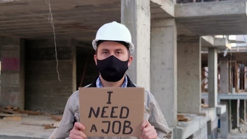 Man with Sign "I Need A Job" on Construction Site