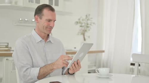 Man Using Tablet Sitting at a Table
