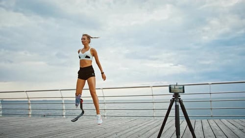 Mujer discapacitada grabando Vídeo tutorial motivacional ejercitándose en la playa