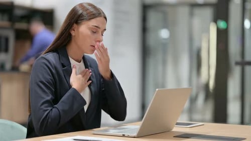 Sick Businesswoman with Laptop Coughing in Office