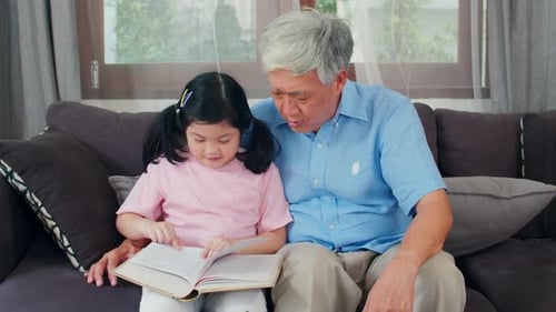 Loving Grandfather Reads with Child on Couch