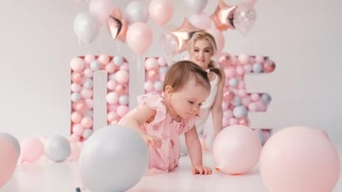 Baby Girl Plays with Balloons at Birthday Party