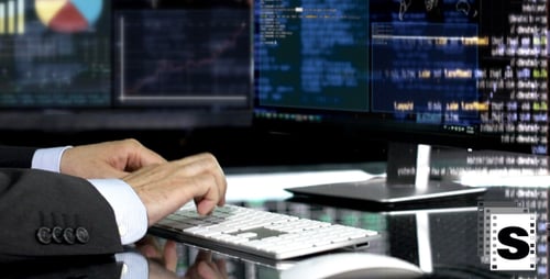 Man Typing on Keyboard in Front of Monitors