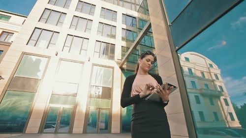 Young Woman Uses Tablet Outside Modern Building