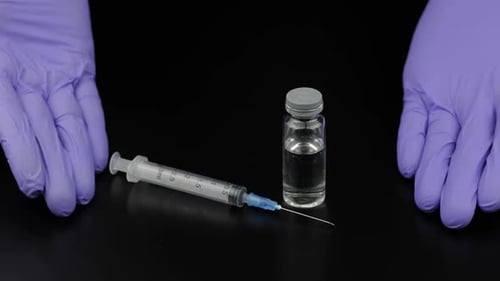 Gloved Hands with Syringe and Medical Vial