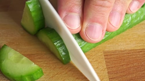 Amateur Cooking Of Greek Salad. Part Of The Set. Cutting Cucumber Shot