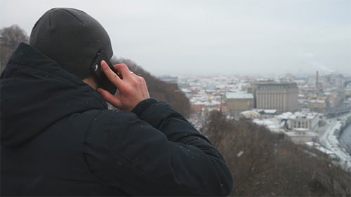 Man Talking on Phone Overlooking City in Winter