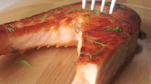 Ein Stück frisch gekochtes Lachssteak mit einer Gabel nehmen