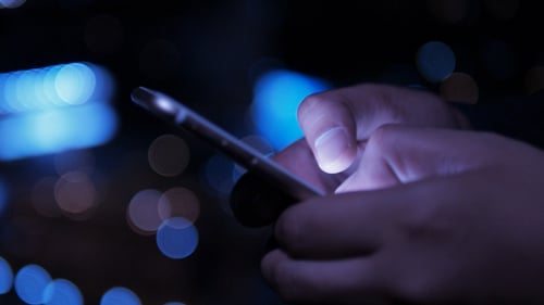 Hands Using Smartphone at Night in City