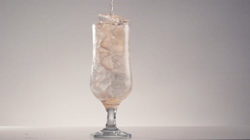 Pouring a Beverage Into Glass with Ice