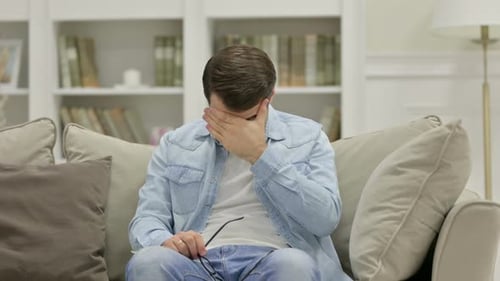 Gestresster junger Mann mit Kopfschmerzen zu Hause