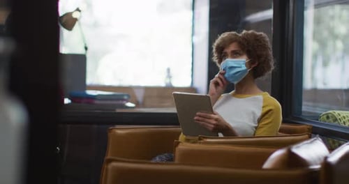 Mujer afroamericana con máscara facial con tableta digital en una oficina moderna