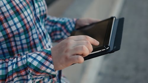 Of Man In a Plaid Shirt Uses The Tablet Outdoor