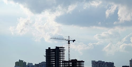 Construction Site Silhouette with Tower Crane and Cloudy Sky
