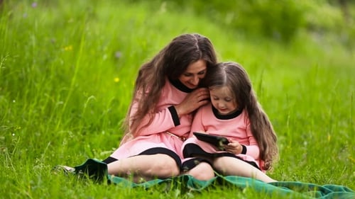 Mother and Daughter Using Tablet in Grassy Field