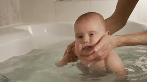 Infant Enjoying Bath Time Assisted by Adult Hands