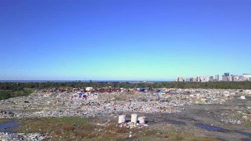 Drone view of city dump on background of sea, the city and the mountains.