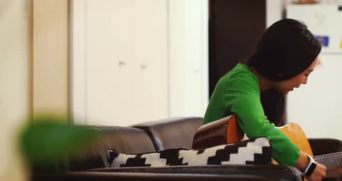 Woman Plays Acoustic Guitar in Living Room