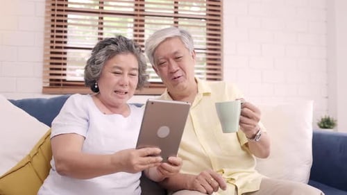 Senior Couple Laughing Together While Using Tablet at Home