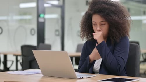 Woman in Office Coughing While Working on Laptop