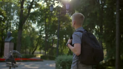 Side View of a Student Photographer Is Walking Along a European Town Street Behind Him