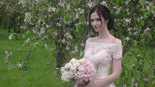 Beautiful Bride in Blossoming Garden with Pink Bouquet