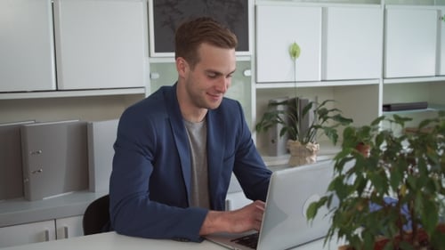 Happy Businessman Working On The Laptop In The Modern Office.