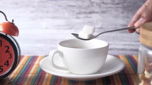 Adding Sugar to Cup of Coffee with Spoon