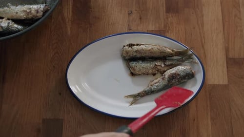 Serving Delicious Fried Sardines onto a Plate