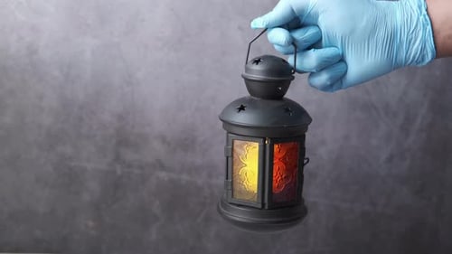 Hand in Handschuhen mit Laternenlicht vor schwarzem Hintergrund