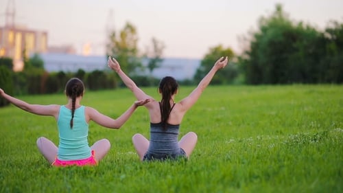 Women Doing Yoga in Grassy Field at Sunset