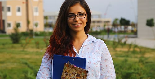 Smiling Student Holding Notebook on Campus