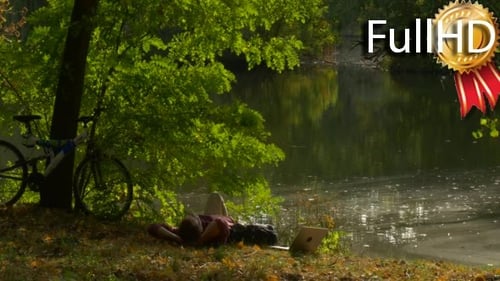 Man is Sitting at Lake Bank Working With Laptop