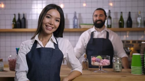 Smiling Cafe Employees Behind Counter with Macarons