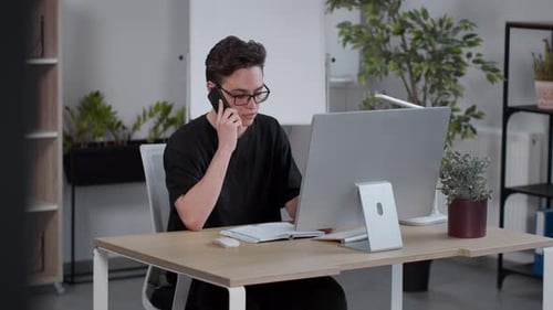 Junger talentierter Geschäftsmann mit Brille Beratung Kunden über Smartphone Online arbeiten an